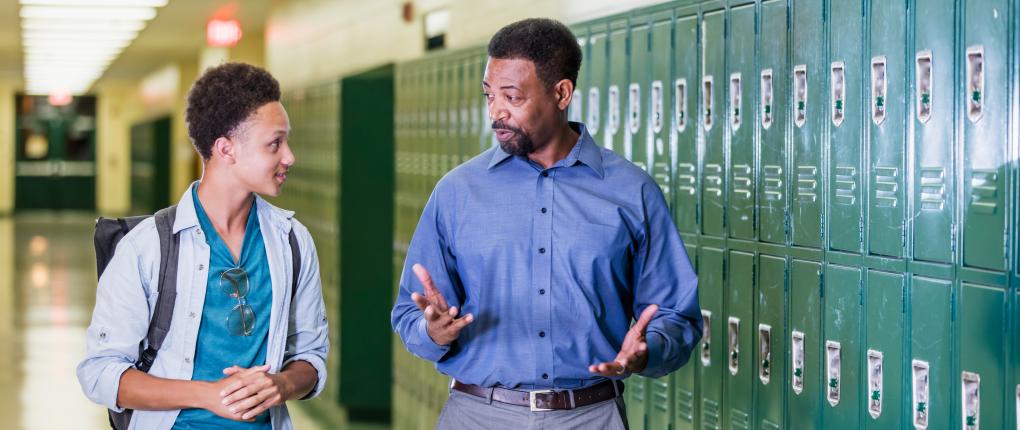 Teacher and high school student walking in hallway