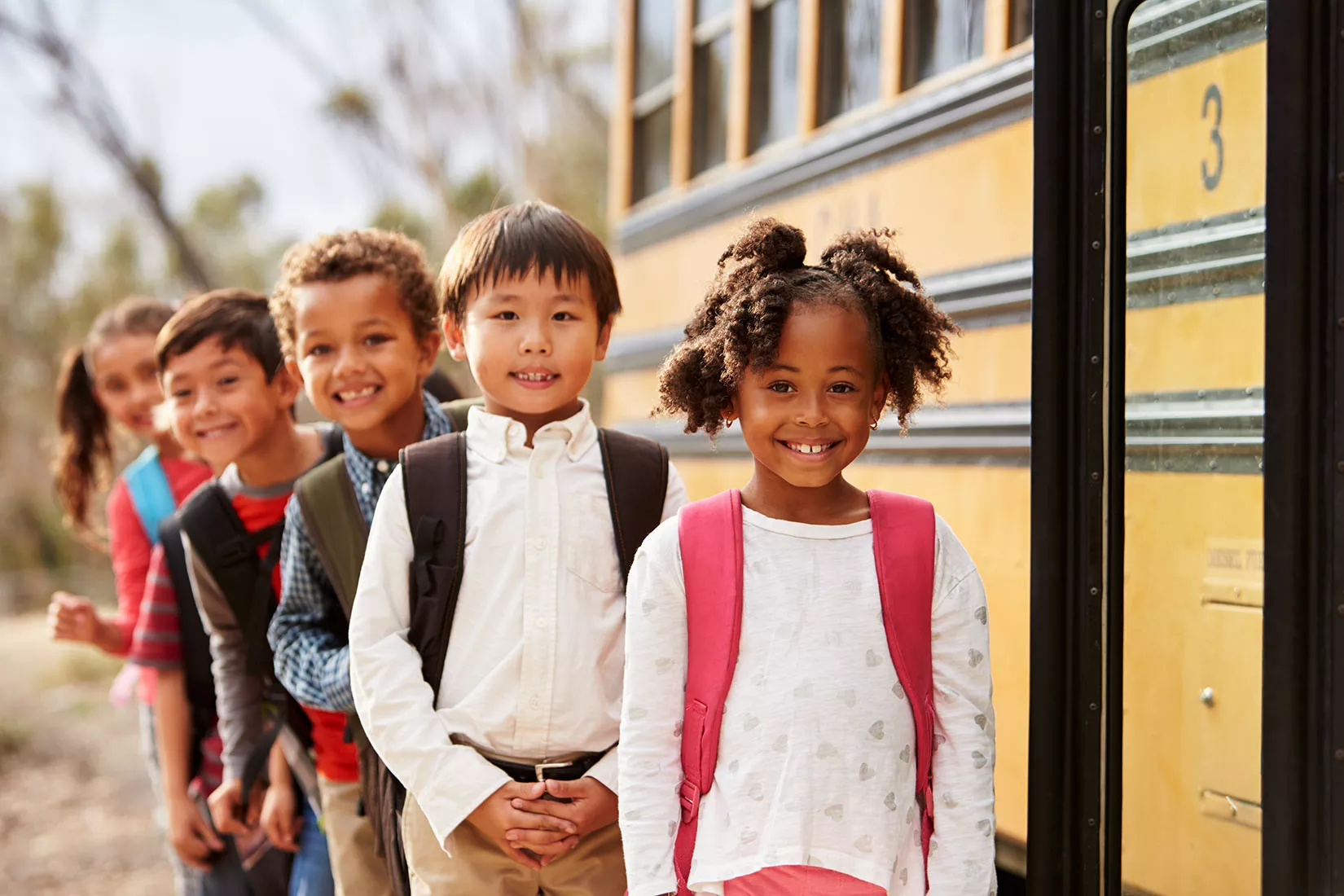 Line of children outside a school bus waiting to board for school