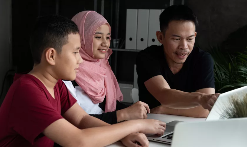 Students looking at laptop screens and pointing